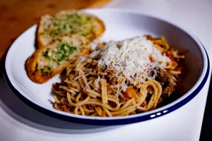 Spaghetti Bolognese topped with parmesan, served with garlic bread