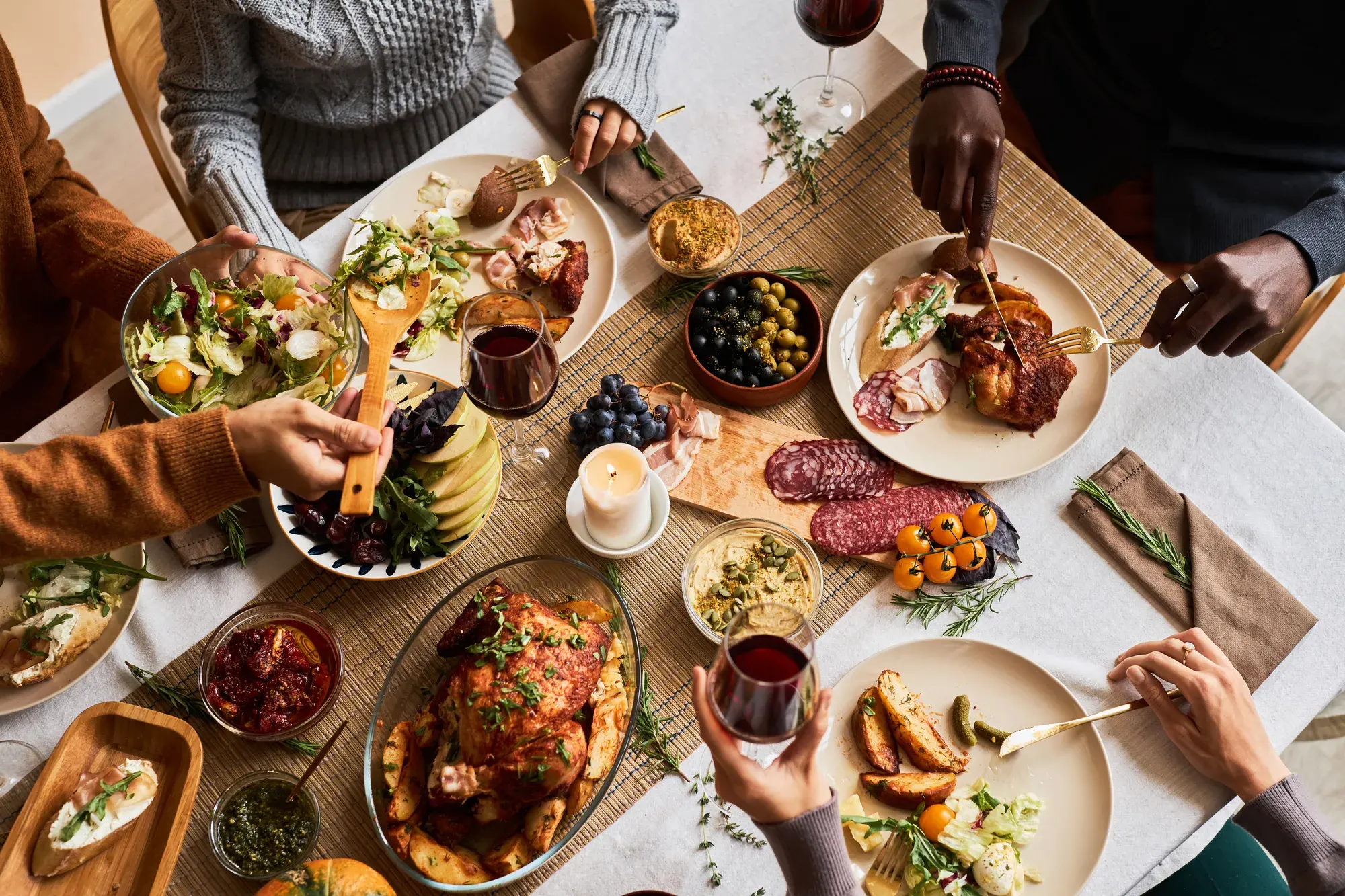 Friends gathered around a table sharing a spread of roast chicken, salads and small plates